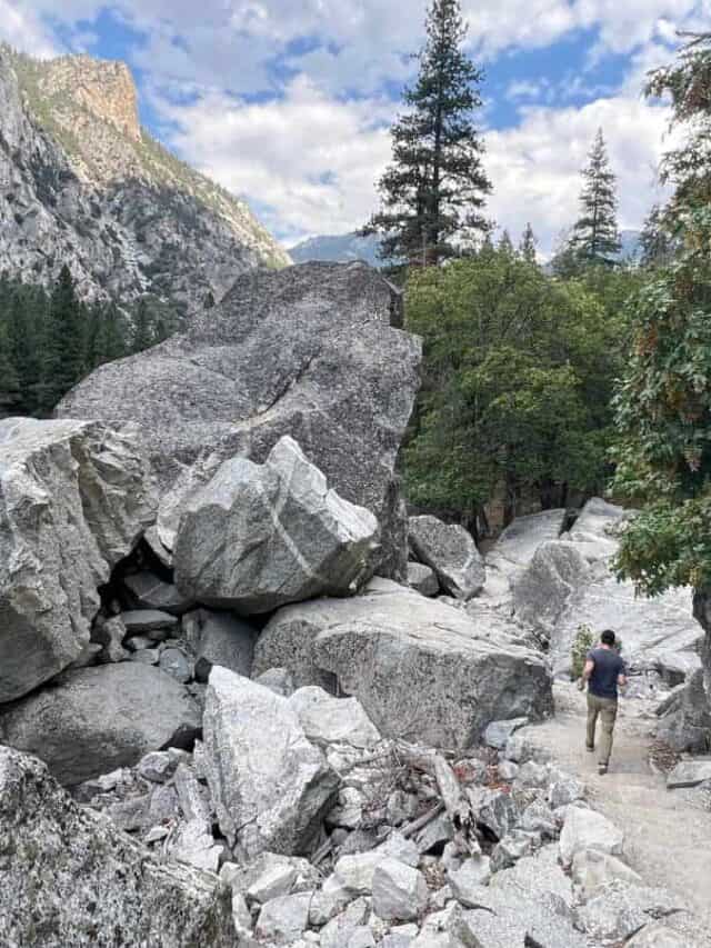A man walks on a path surrounded by giant boulders in Kings Canyon.