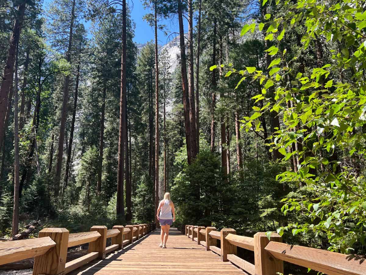 A woman walks across a wooden footbridge in Yosemite National Park, California.