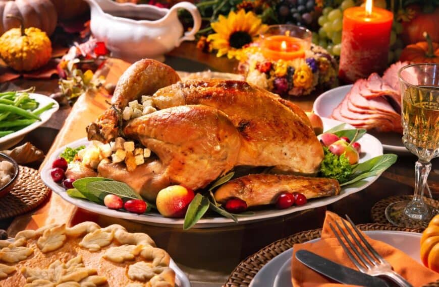 A large turkey platter sits on a table surrounded by side dishes for a Thanksgiving feast.