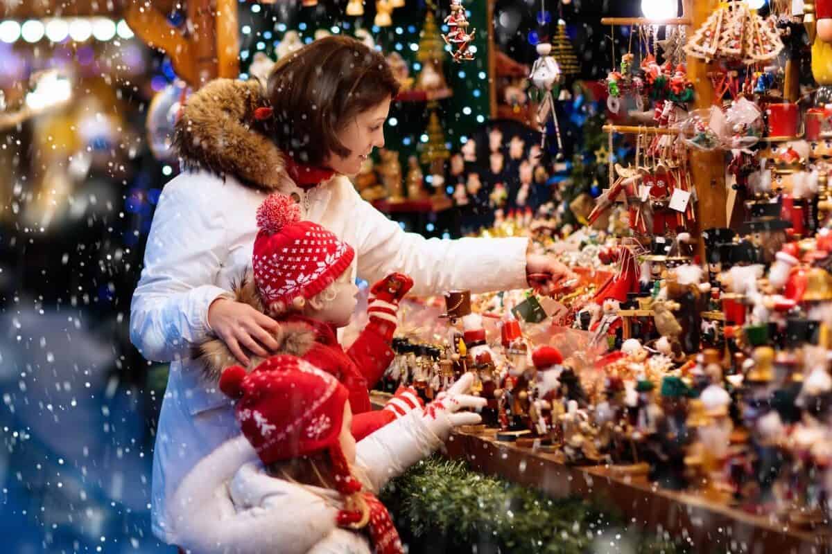 A woman and two young children shop at a Christmas market.