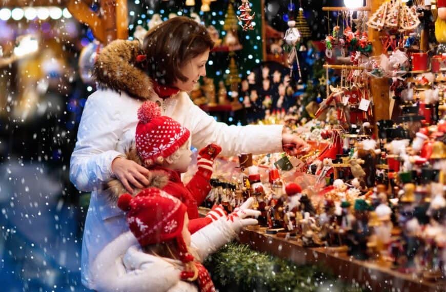 A woman and two young children shop at a Christmas market.