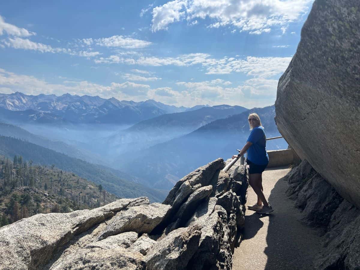 A woman pauses on Moro Rock Trail in Sequoia National Park to look at the mountains on the horizon.