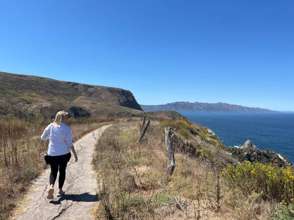 A woman hikes a path along the coast of Santa Cruz Island, CA.