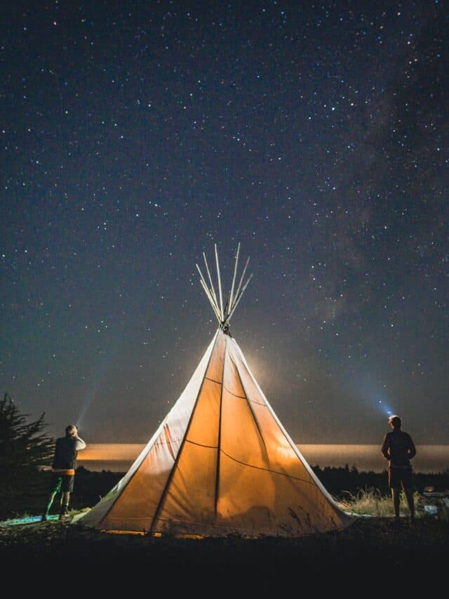 two person standing beside tent during nighttime