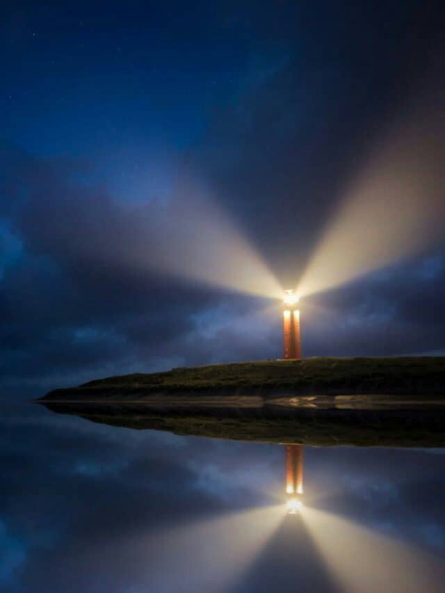 lighted brown lighthouse beside body of water