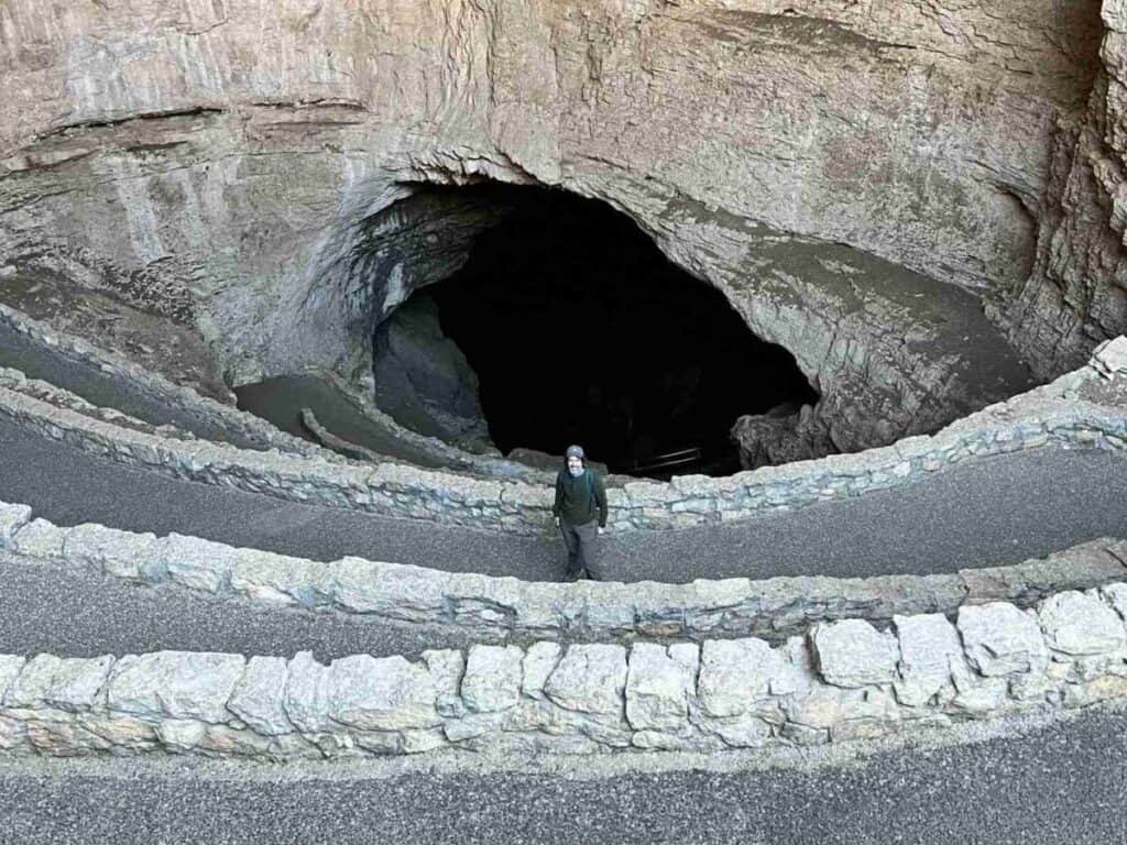 A man poses for a picture in front of the Natural Entrance to Carlsbad Caverns