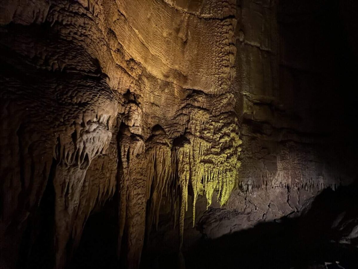 Stalactites have a green hue under the lights in a cave