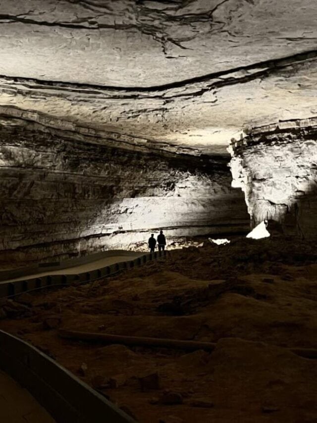 Silhouettes of a man and woman appear in the distance on a long passage in Mammoth Cave