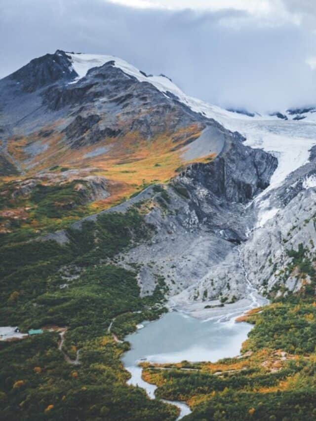a snow covered mountain range with a lake below