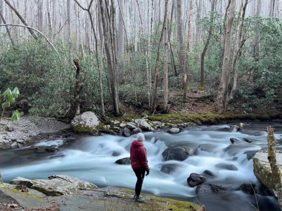 A woman states at a rushing river in the Smokies