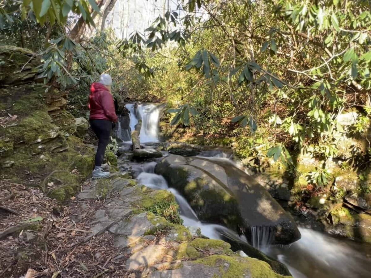 A woman gets a close view of a small waterfall