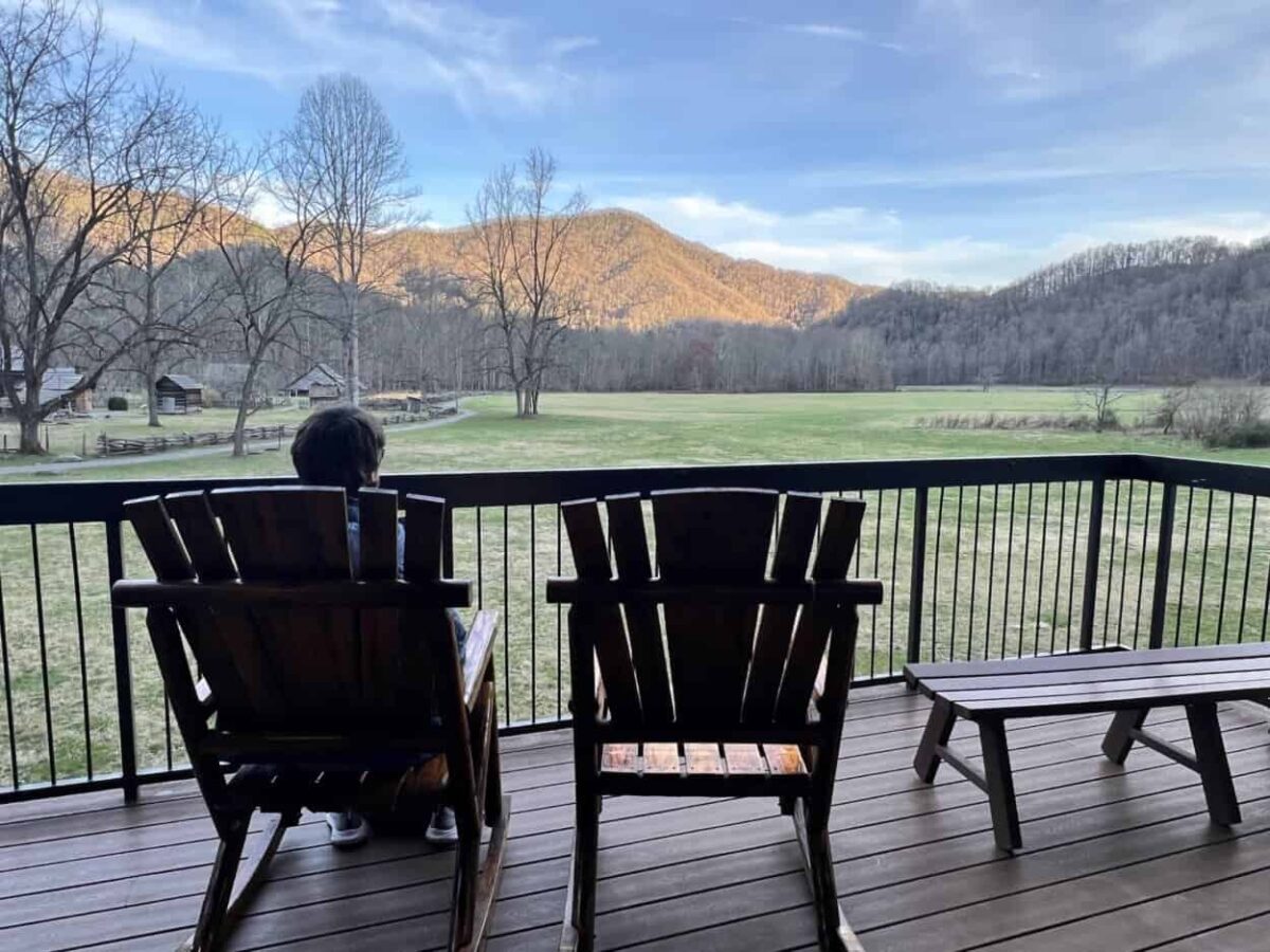 A man sits in a chair, enjoying the view of mountains on the horizon.