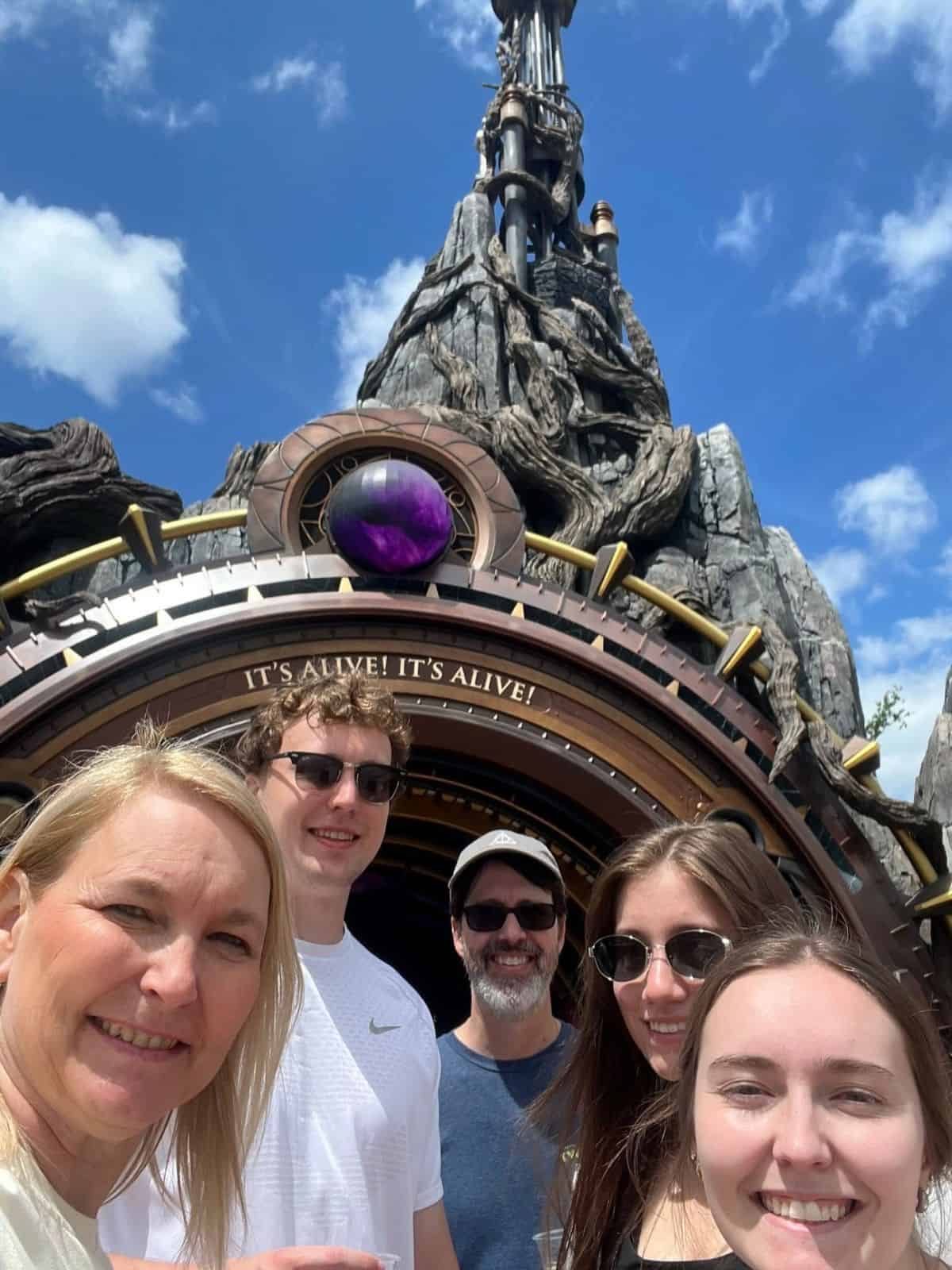 The Miles with McConkey family poses for a picture in front of the Dark Universe portal in Epic Universe, Orlando, FL.