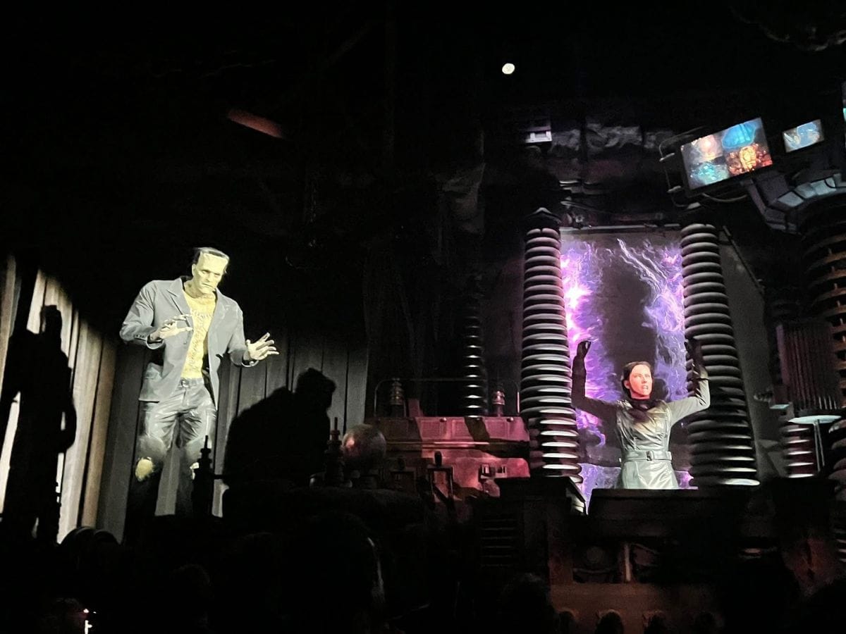 Frankenstein's Monster and Dr. Victoria Frankenstein animatronic characters speak to the crowd on the Monsters Unchained ride at Epic Universe.