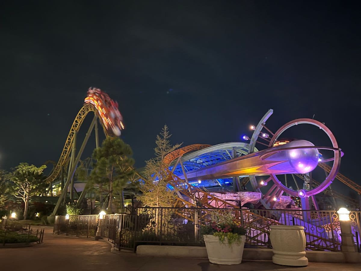 A roller coaster crests the top of a hill at night in Epic Universe.