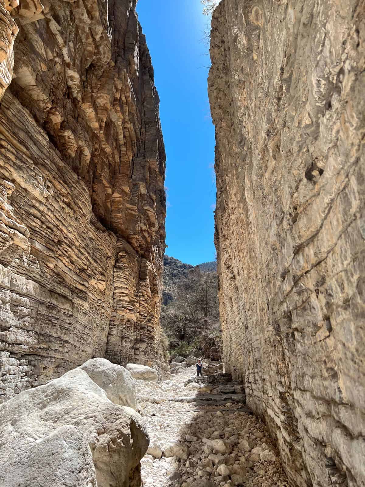 A man stands between two towering canyon walls