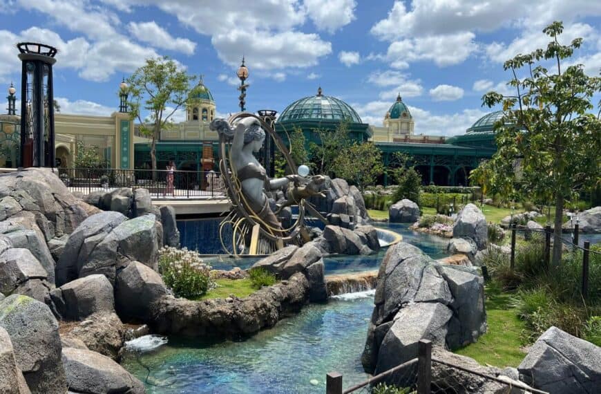 A statue of Luna rises above a fountain pool with a solarium in the background.