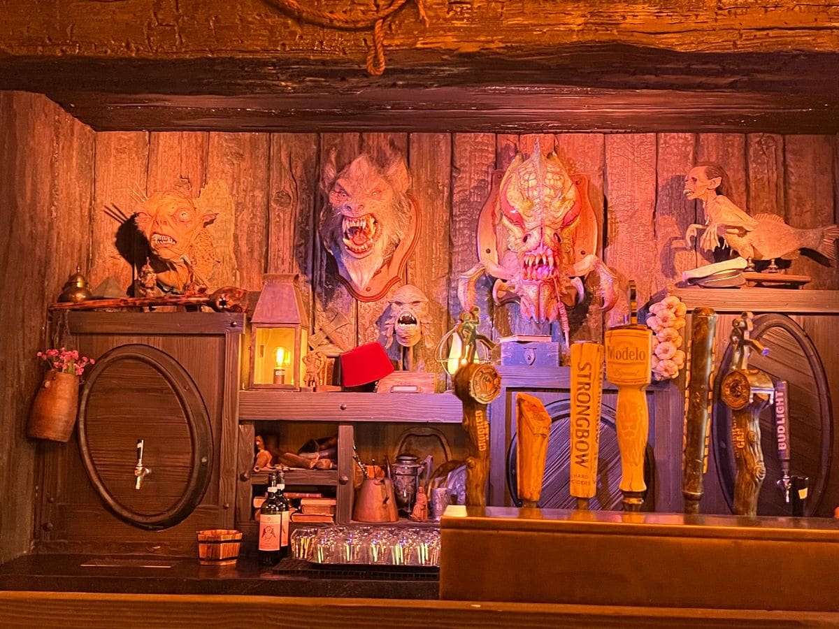 Monster memorabilia hangs on the walls behind the bar at the Burning Blade Tavern in Dark Universe at Epic Universe.