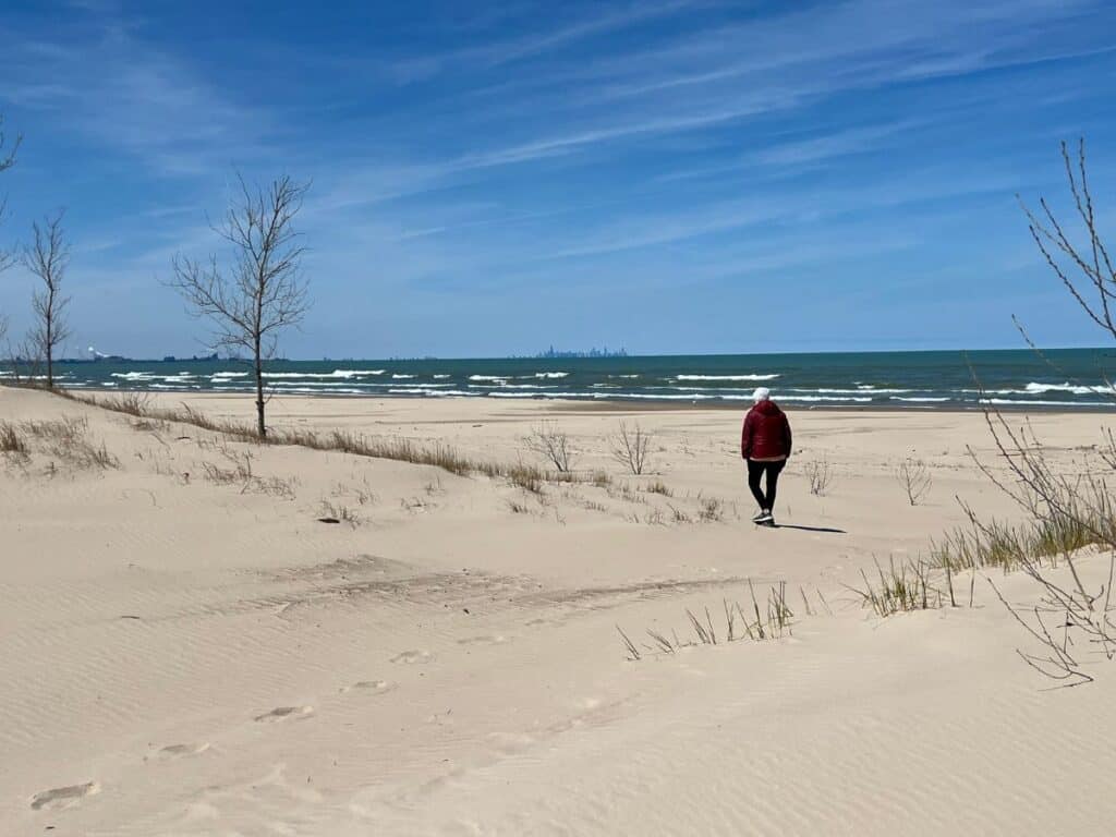 A woman walks a beach along Lake Michigan. Views of the Chicago skyline make Indiana Dunes National Park worth visiting.