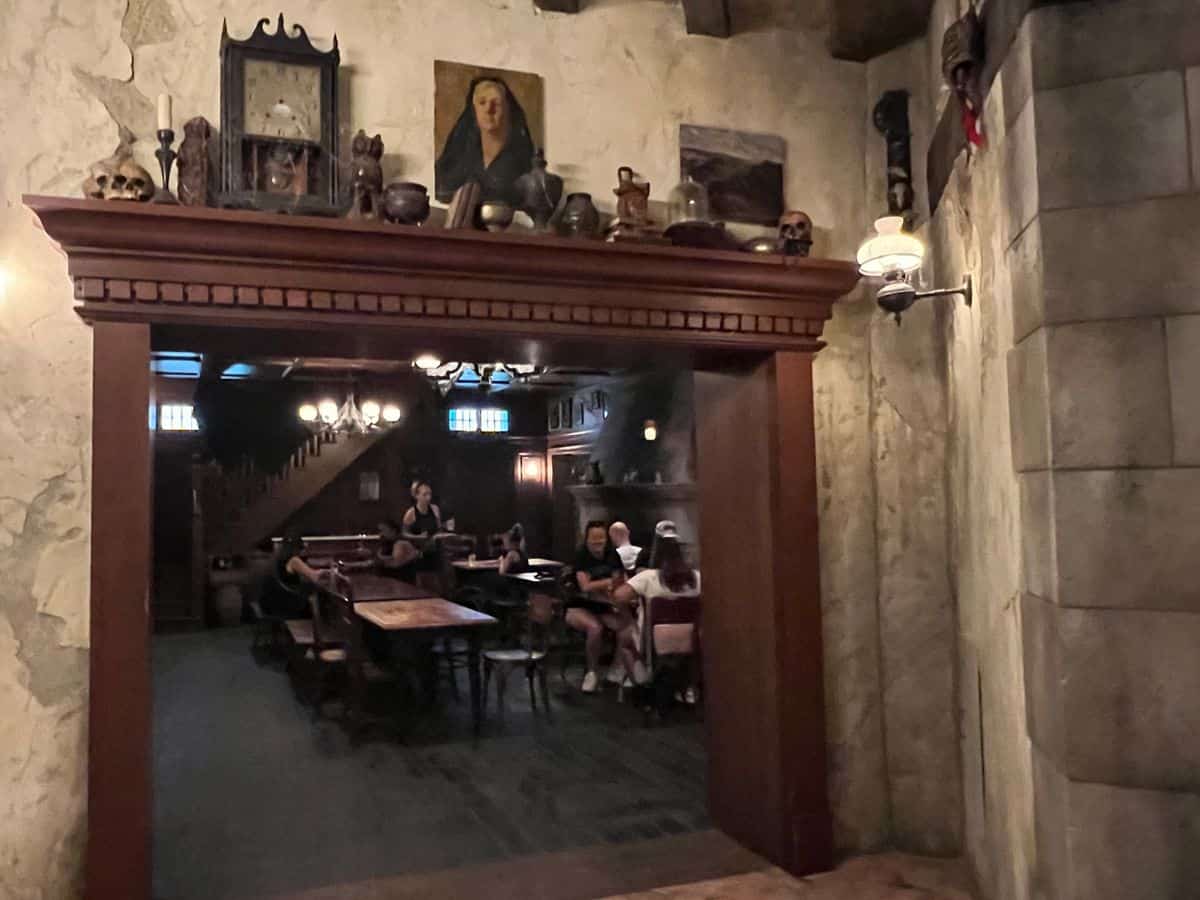 Guests relax in a dark tavern in Epic Universe's Ministry of Magic land