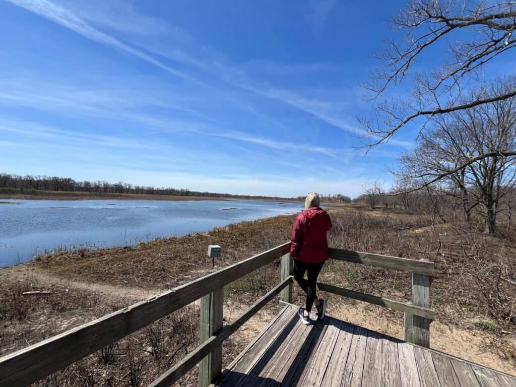 A woman stands on a platform looking for birds on Long Lake, near West Beach, Indiana Dunes National Park, IN.