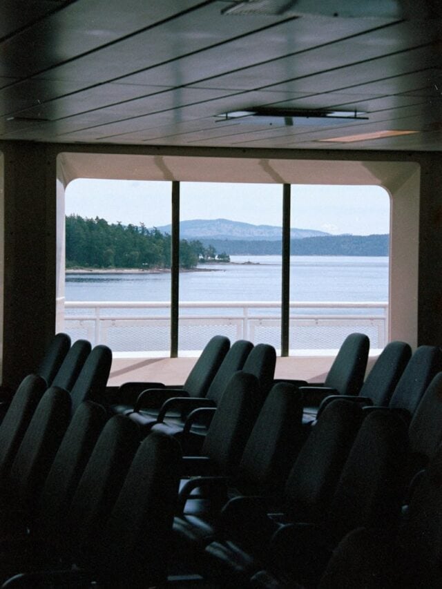 A row of black chairs sitting in front of a window on a scenic ferry