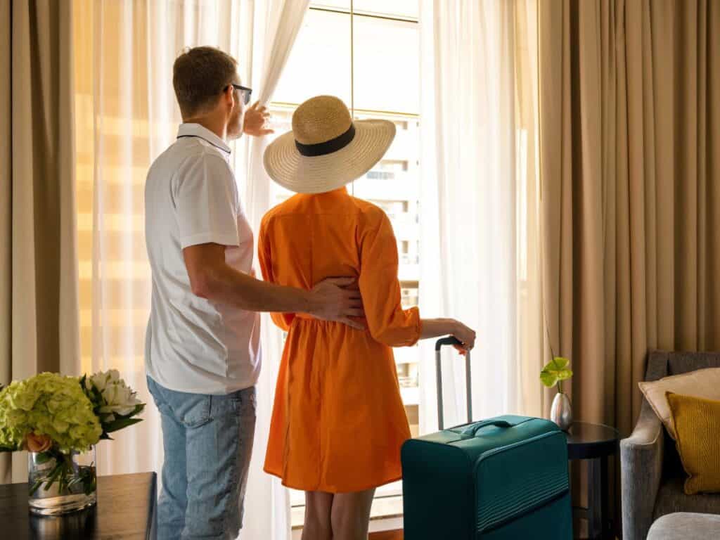 A couple looks out a hotel window after arriving.