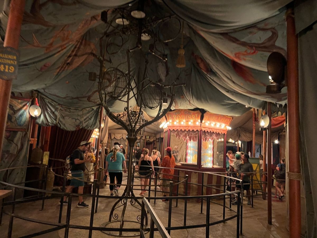 Guests walk under circus tents on their way to see a show in Epic Universe's Ministry of Magic world.