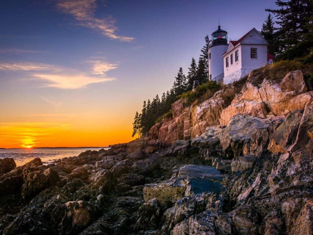 The sun sets behind Bass Harbor Lighthouse, Acadia National Park, Maine
