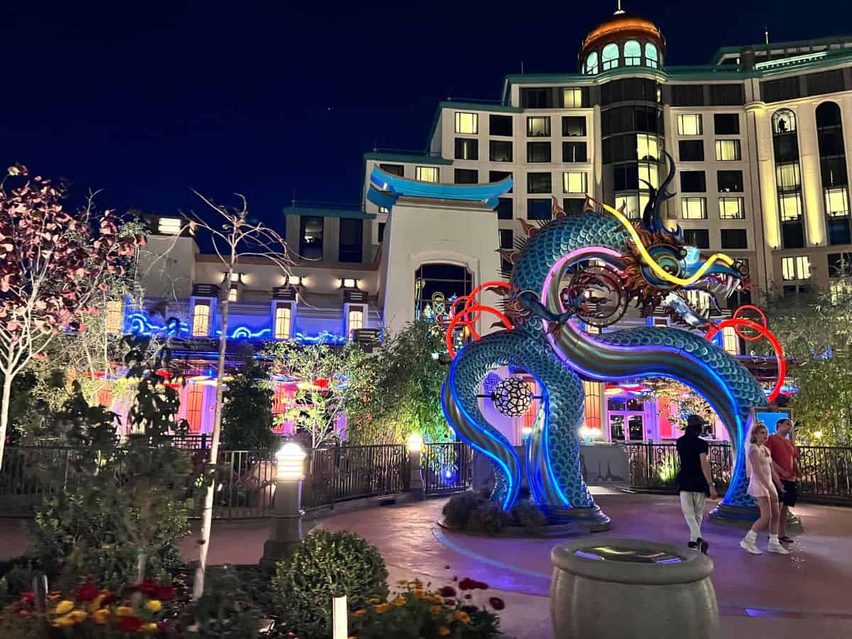 Guests walk under a giant illuminated blue dragon in Epic Universe