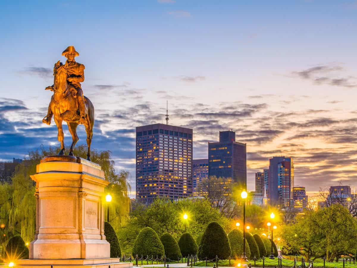 A statue of a colonial American patriot on horseback stands before the Boston skyline