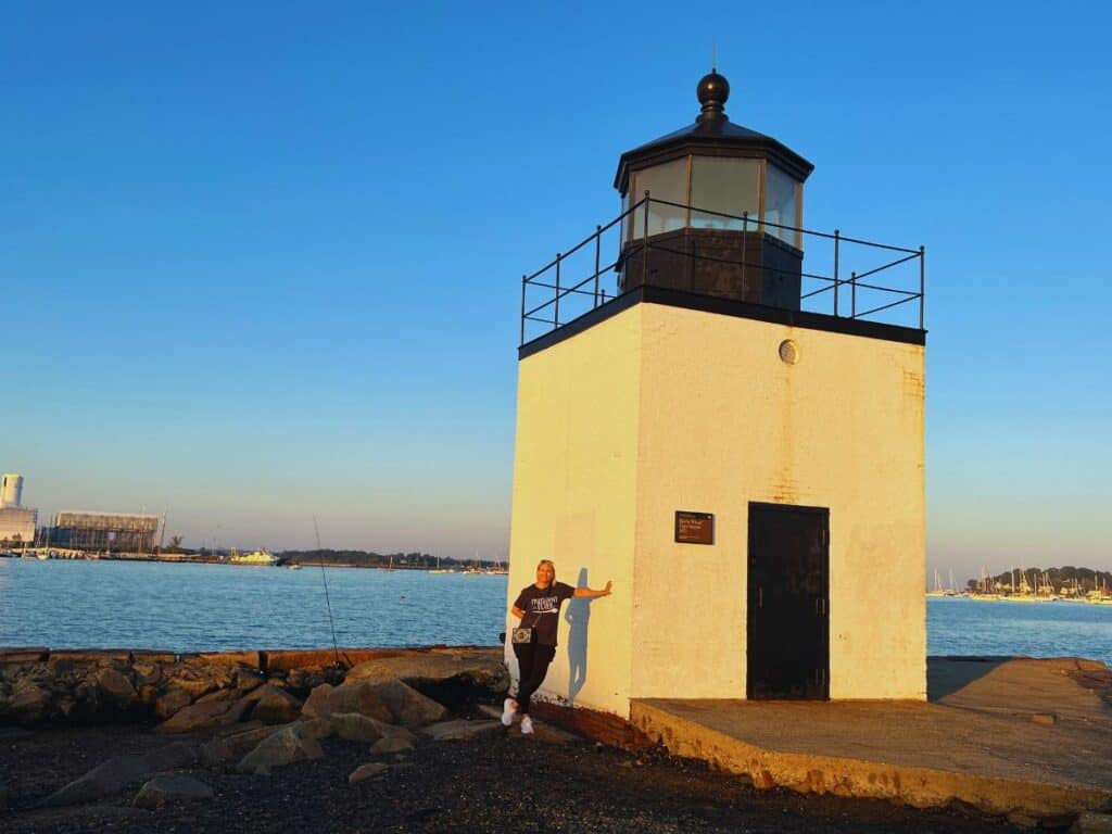 A woman leans against the Derby Wharf Light Station for a photo op