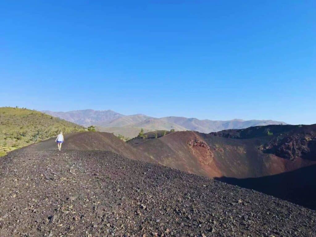 A person walking on a dirt road in the middle of a volcano in Craters of the Moon National Monument & Preserve, Idaho.