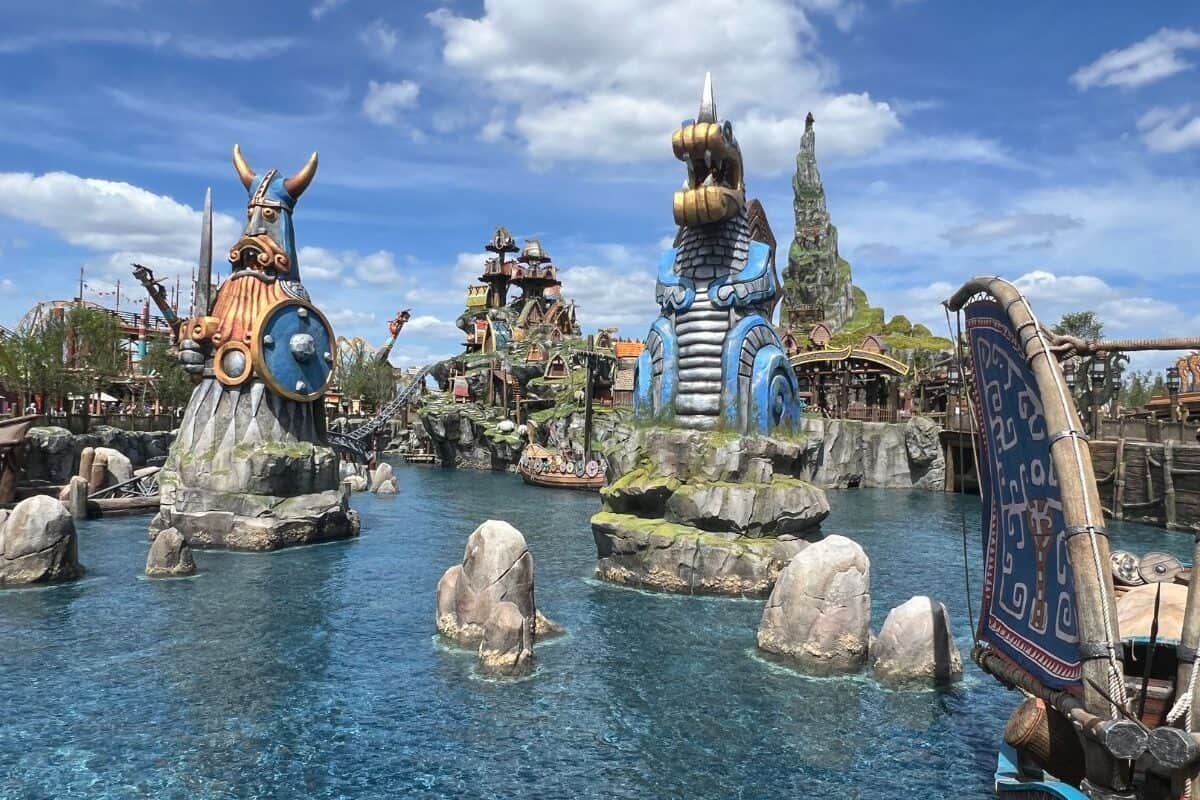 A giant Viking statue and a giant dragon statue tower out of the water in the Isle of Berk in Epic Universe