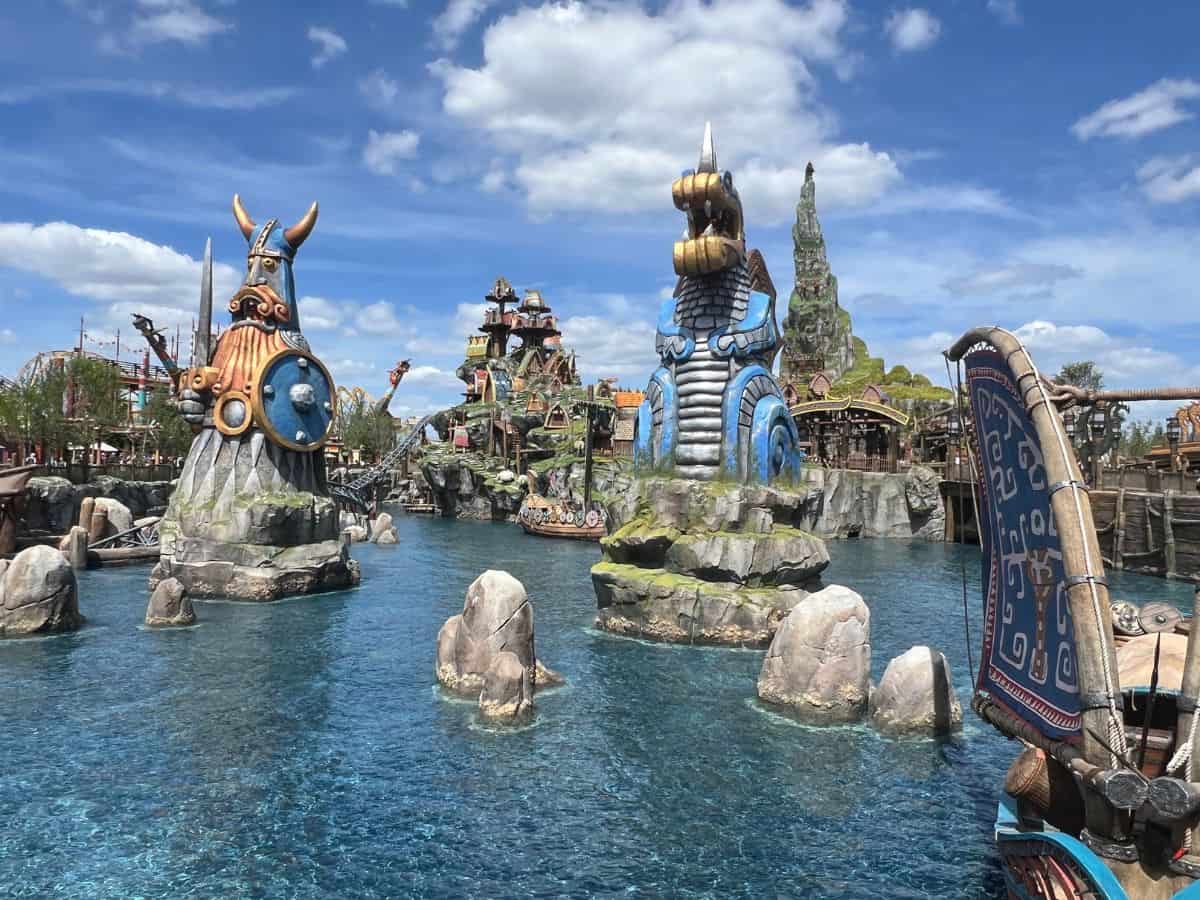 A giant Viking statue and a giant dragon statue tower out of the water in the Isle of Berk in Epic Universe