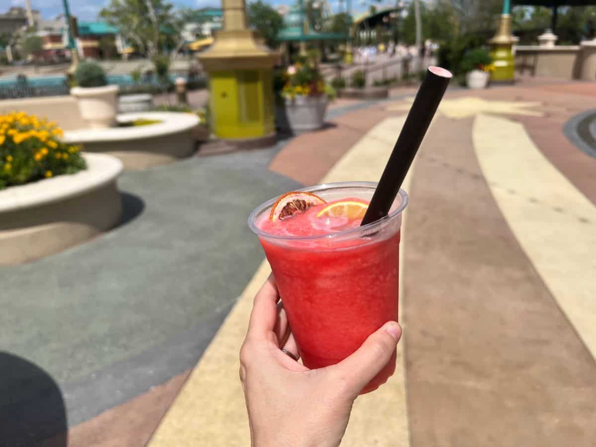 A hand holds a cup with a frozen red cocktail in Celestial Park at Epic Universe, Orlando, FL