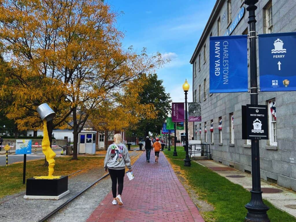 A woman walks along a red brick sidewalk in Boston on a lovely autumn day