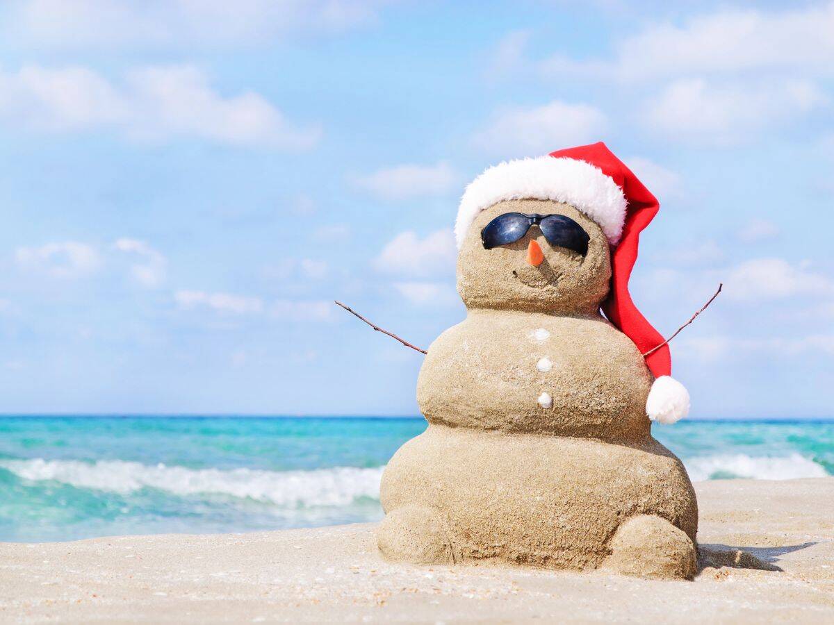 A sandy snowman represents Christmas in July travel - some locations celebrate the popular holiday in summer for a fun twist.