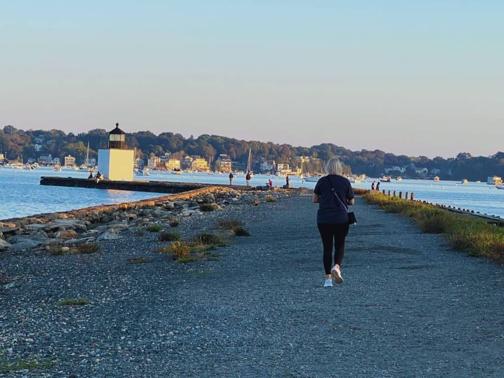 A woman walks along the path toward the Derby Wharf Light in Salem, Massachusetts