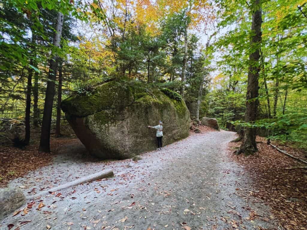 A woman hugs a giant glacial boulder