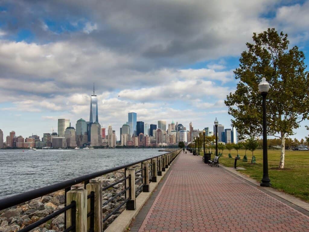 A brick sidewalk stretches along the water with a view of Manhattan in Liberty State Park, NJ
