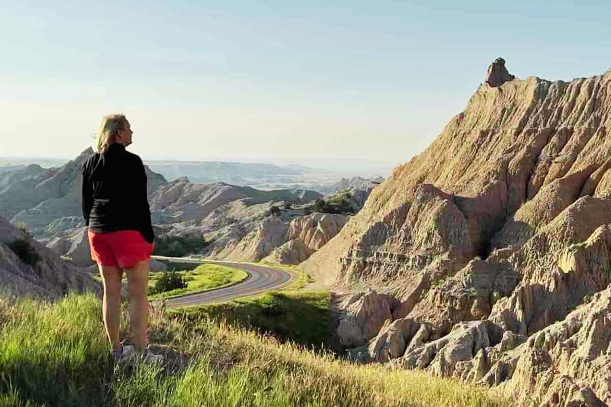 A woman looks at a road that winds downward through Badlands National Park, South Dakota