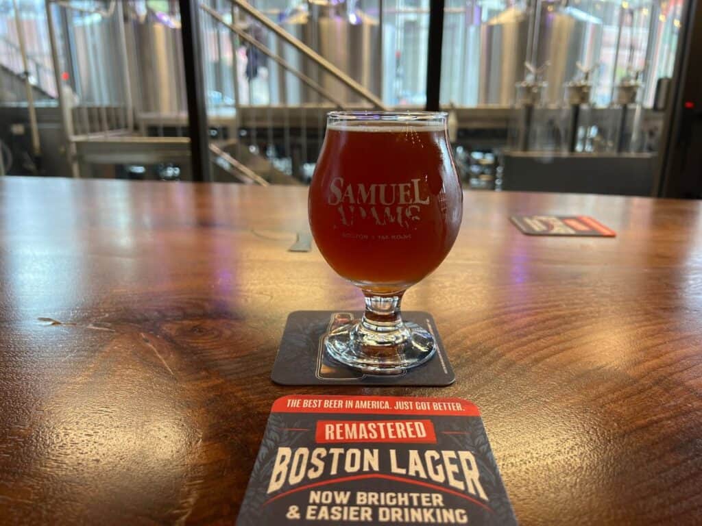 A glass of beer and a coaster sit on a table in the Downtown Boston Samuel Adams Taproom - a great place to refresh when walking the Freedom Trail