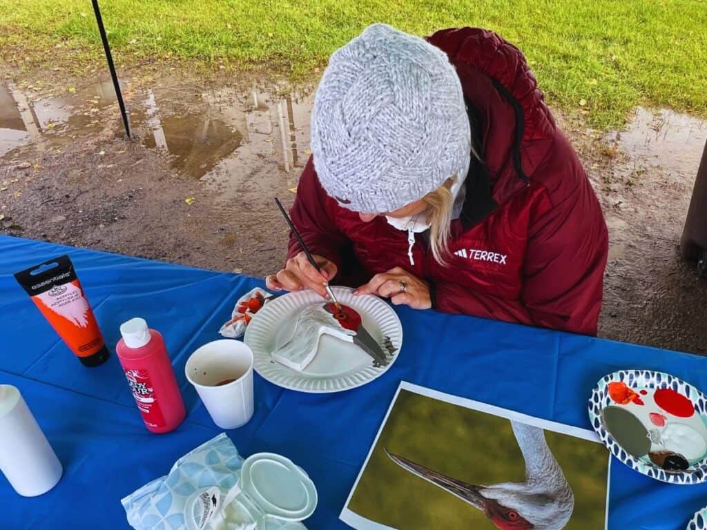 A woman paints a wooden sandhill crane at the Tanana Valley Sandhill Crane Festival.