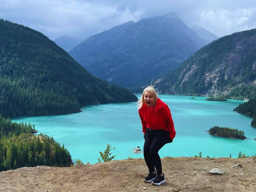 A woman rejoices at the view of turquoise water surrounded by mountains, Diablo Lake, North Cascades National Park, WA