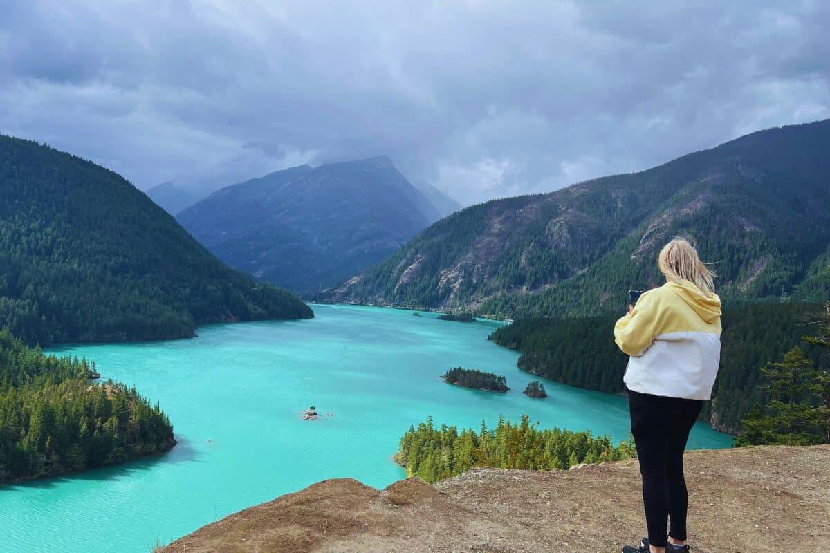 A woman takes a picture of Diablo Lake with her phone.