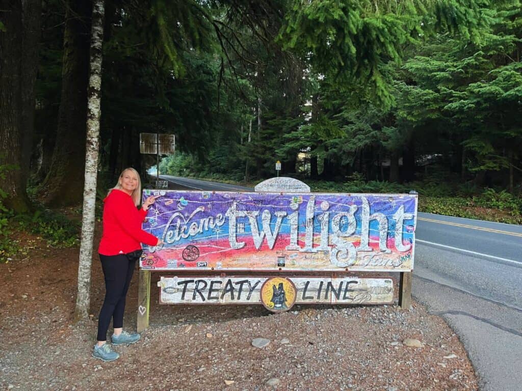 A woman poses with a Twilight sign in Forks, Washington