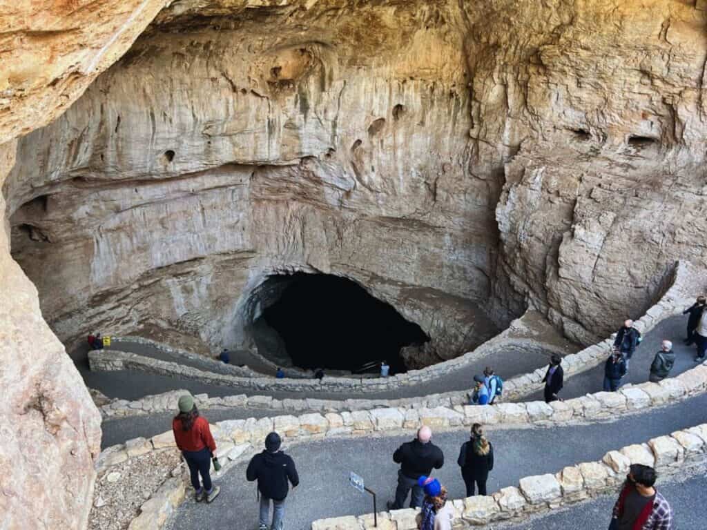 Carlsbad Caverns National Park visitors walk down steep switchbacks, into the cave entrance.