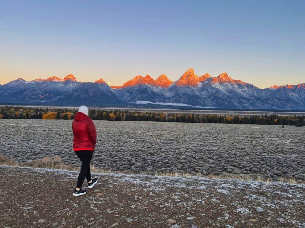 A woman walks forward for a closer view of sunrise at Glacier Point, Grand Teton National Park, WY.