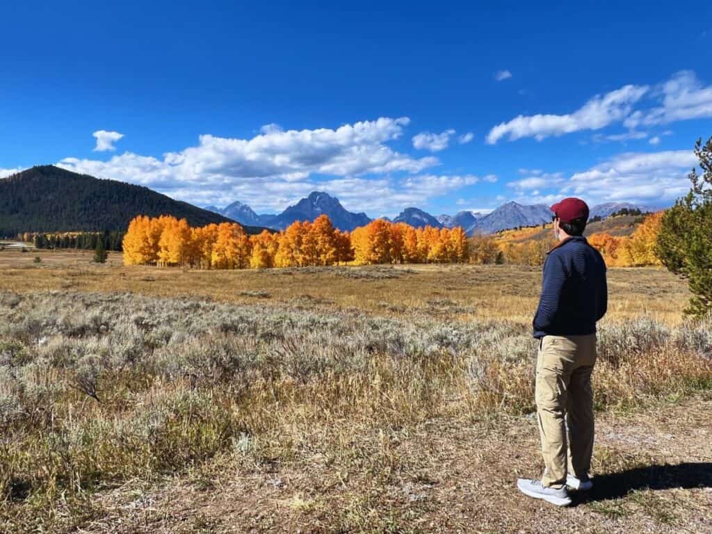 A man savors the view of fall foliage and mountains in Grand Teton National Park, Wyoming.